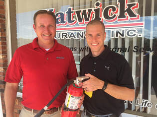 Photo of Natwick Insurance founders, Erik and Kyle, holding a fire extinguisher in front of their office
